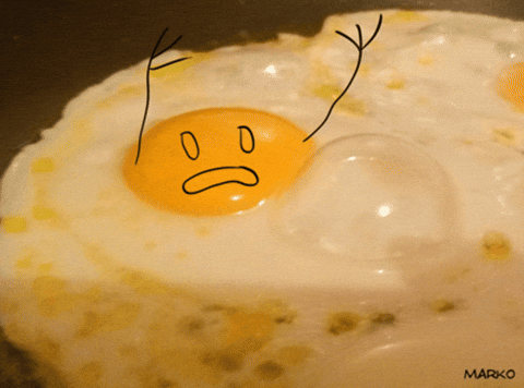 A fried egg with eyes, an open mouth, and waving hands drawn onto it