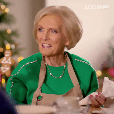 Mary Berry laughs while holding a gingerbread cookie that's wearing a bikini