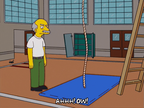 A Simpsons character pulling a blue mat out from under a rope before Milhouse falls to the ground