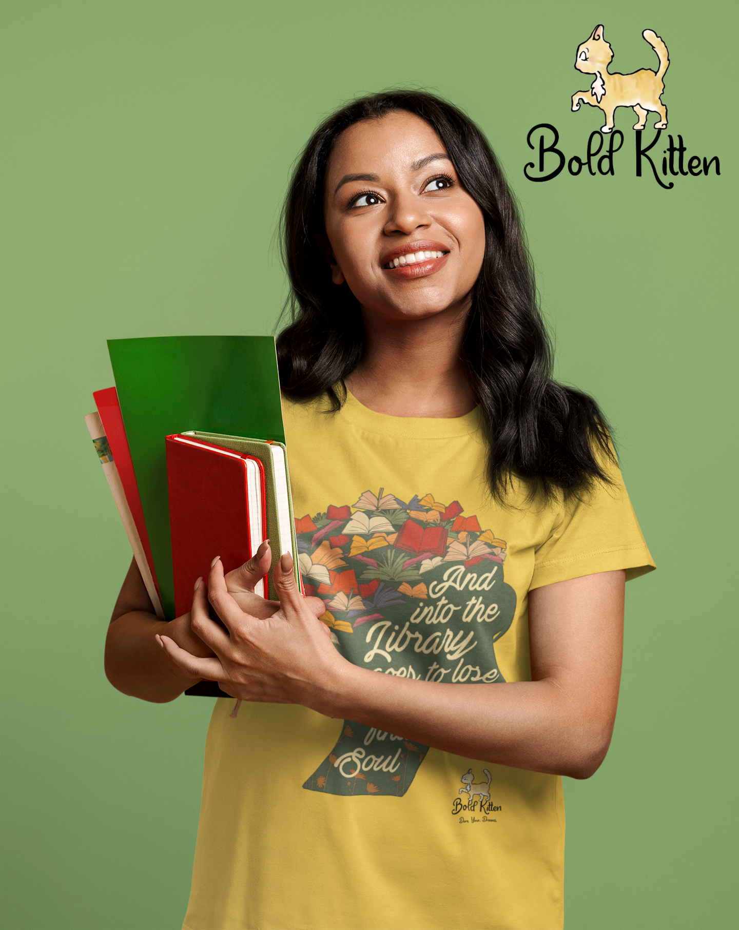 A brown woman with straight black hair is holding a couple of journals and some folders as she stands  against a kiwi-colored background. She is wearing a daisy-colored t-shirt with a dark yellow-green silhouette head-and-neck with leaves for hair. On the silhouette is written ‘And into the library she goes to lose her mind and find her soul.’ She is looking up at our Bold Circus Kitten, Rocko, who is confidently striding through the air at the top right. He IS a Circus Kitten, after all.