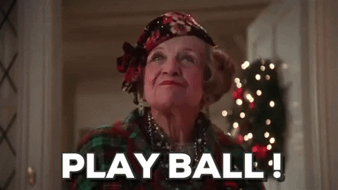 An older woman with a Christmas hat and scarf says "PLAY BALL!" 