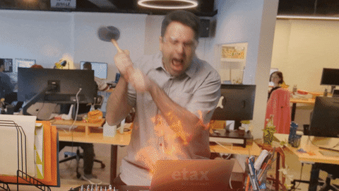 a man hits his flaming computer with a hammer