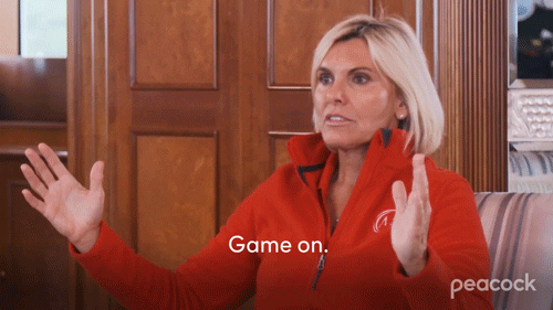 A person in a red sweater holding her hands wide and saying "Game on"