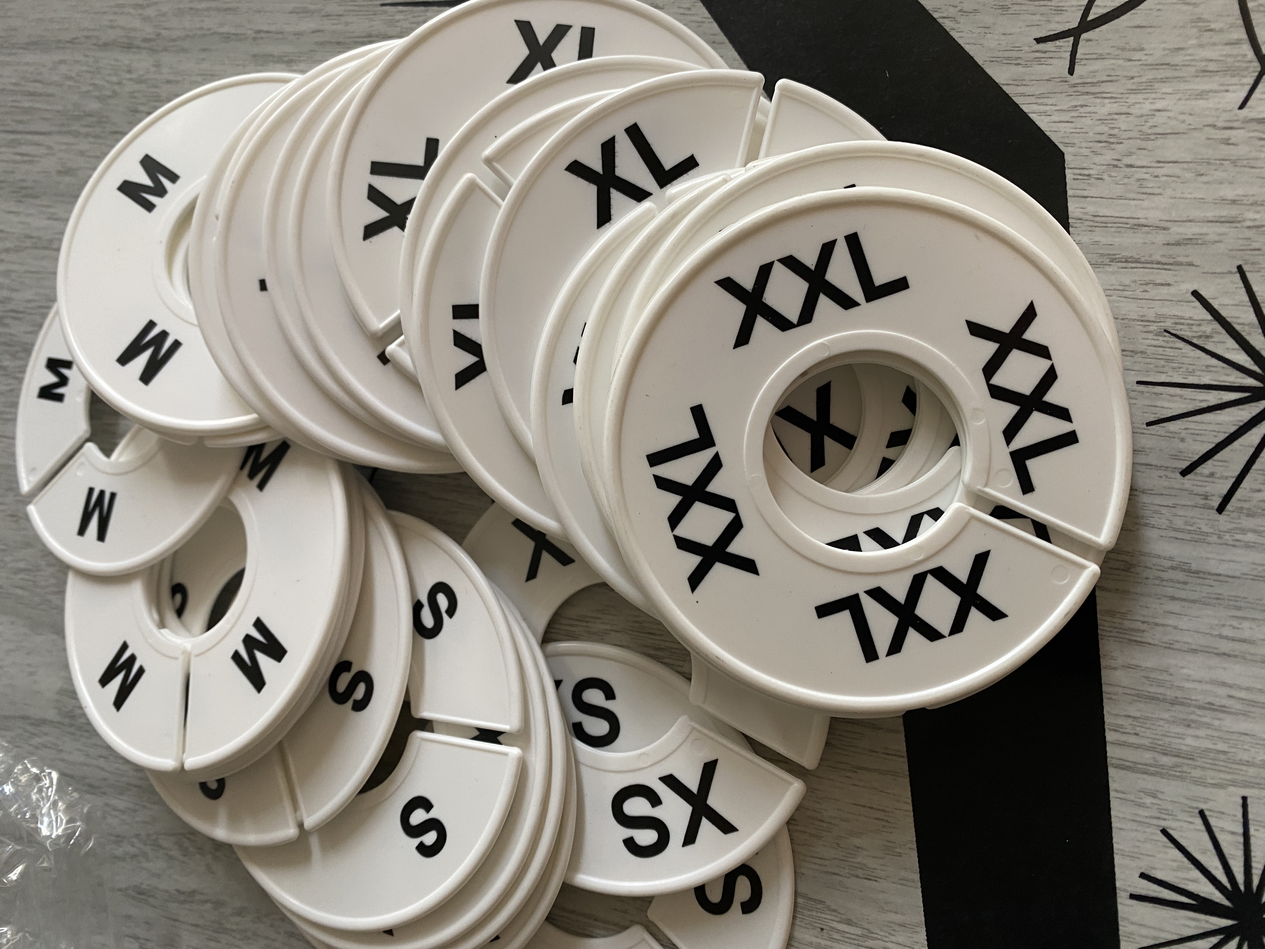 A pile of round clothing size markers, ranging from XS to XXL