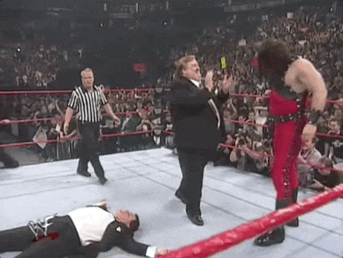 A person in a tux lying on a wrestling ring's floor