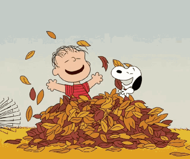 Linus and Snoopy in a pile of fall leaves, throwing them in the air